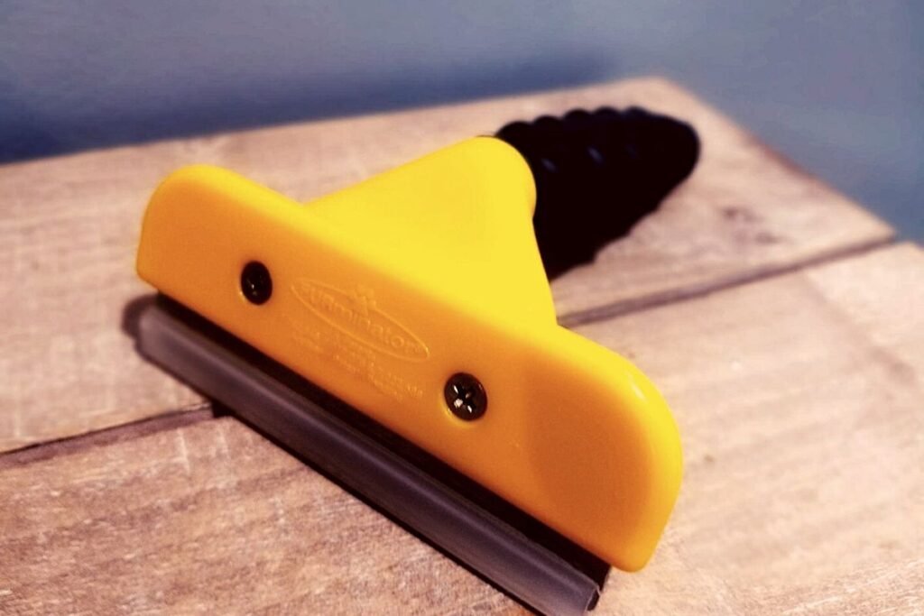 Photo of yellow Furminator dog brush which is one of the best ways to deal with Labrador shedding.