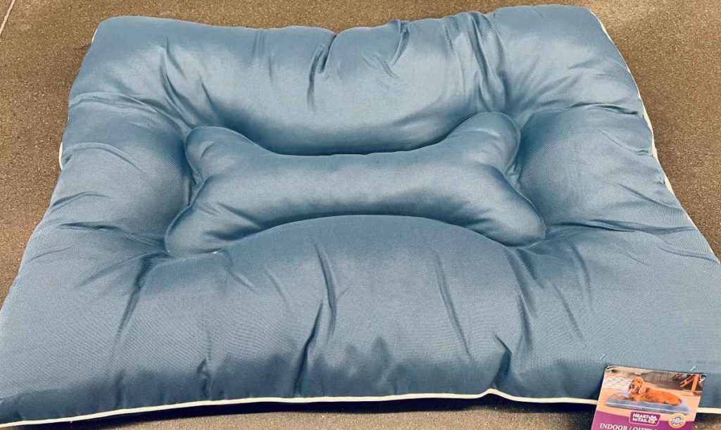 Blue dog bed with a shape of a dog bone on it.